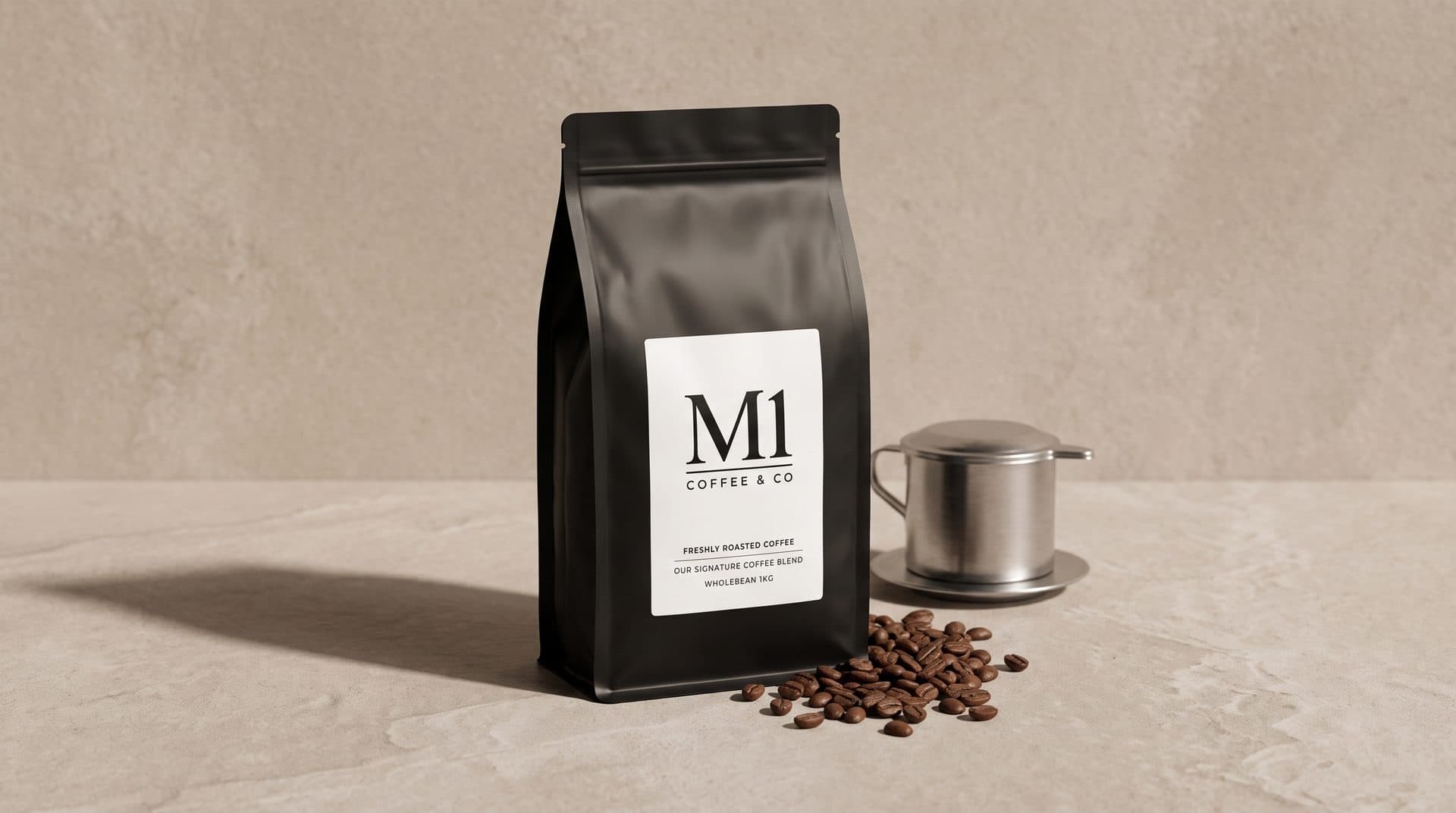 A matte black 1kg bag of M1 Signature Blend wholebean coffee with a phin filter and loose beans